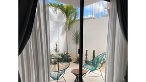 A modern living room with a sliding glass door leading to a patio area. - Discover Your Tulum Sanctuary Stylish Studio in Vibrant La Veleta! (Tulum)