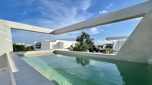 A modern pool area with clear water, surrounded by white architecture and a clear sky. - Discover Your Tulum Sanctuary Stylish Studio in Vibrant La Veleta! (Tulum)