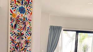 A modern room with a large window, a view of the outdoors, and a colorful abstract painting on the wall. - Discover Your Tulum Sanctuary Stylish Studio in Vibrant La Veleta! (Tulum)