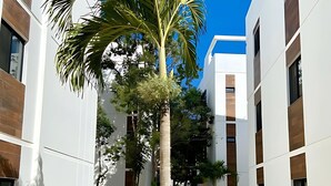 A modern building with a central courtyard featuring a palm tree and surrounding greenery. - Discover Your Tulum Sanctuary Stylish Studio in Vibrant La Veleta! (Tulum)