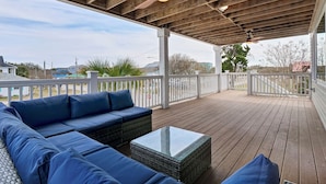 Une terrasse extérieure couverte, dotée d’un plafond en bois, de rampes blanches et de mobilier d’extérieur bleu.