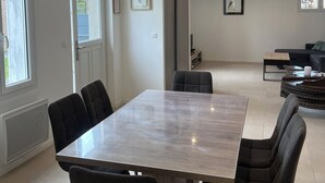 Un espace repas moderne avec une table rectangulaire et six chaises, un canapé et une table basse en arrière-plan.