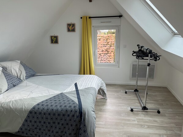 Ein Schlafzimmer mit einem Bett, einem Fenster mit gelben Vorhängen, einem Deckenventilator und einer Wand-Klimaanlage.