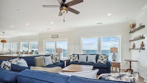 A spacious living room with a large sofa set, a wooden coffee table, and a ceiling fan.