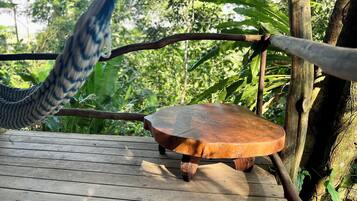 A wooden deck with a hammock and a small wooden table.