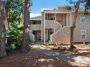 A two-story building with a covered entrance and a staircase leading to the upper floor. - Gorgeous 2nd floor Cottage Near Beach and Pool (Miramar Beach)
