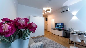 A modern kitchen with a flat-screen TV, a dining area with a white chair, and a flower arrangement on a table. - Luxury apartment 300 meters from Milan Cathedral and Piazza San Babila (Milano)