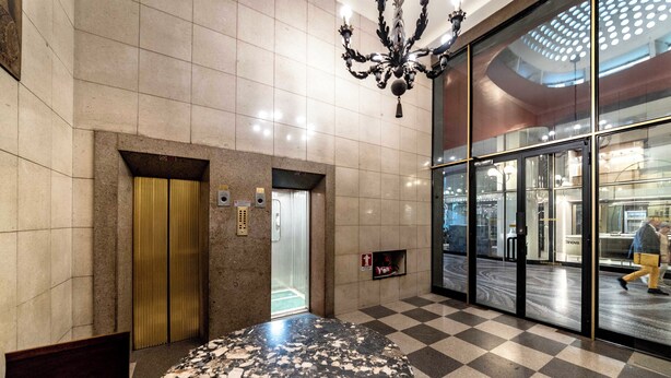 A lobby with a marble table, a chandelier, a checkered floor, and a glass entrance. - Luxury apartment 300 meters from Milan Cathedral and Piazza San Babila (Milano)