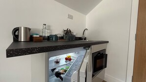 Una cucina con frigorifero integrato, bollitore, un bicchiere e una macchina per il caffè sul piano di lavoro.