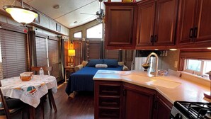 A compact kitchen with wooden cabinets, a stove, and a dining area with a table and chairs.