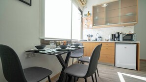 A compact kitchen with a dining table set for four, a microwave, and a small refrigerator. - Athenais 3A 2 bedroom 4 persons apartment by MPS (Athina)