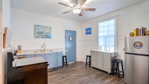 A kitchen with a countertop, sink, and a refrigerator. There is a blue door and a window with blinds. - 1 block to Trolley, Short walk to Historic Cemeteries, Clean, Coffee Bar (New Orleans)