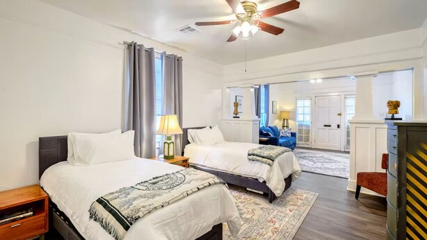 A hotel room with two beds, a ceiling fan, a nightstand, a lamp, a dresser, and a view of the hallway. - 1 block to Trolley, Short walk to Historic Cemeteries, Clean, Coffee Bar (New Orleans)