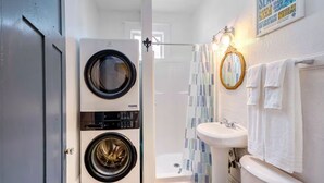 A compact bathroom with a washing machine, a sink, and a shower. - 1 block to Trolley, Short walk to Historic Cemeteries, Clean, Coffee Bar (New Orleans)