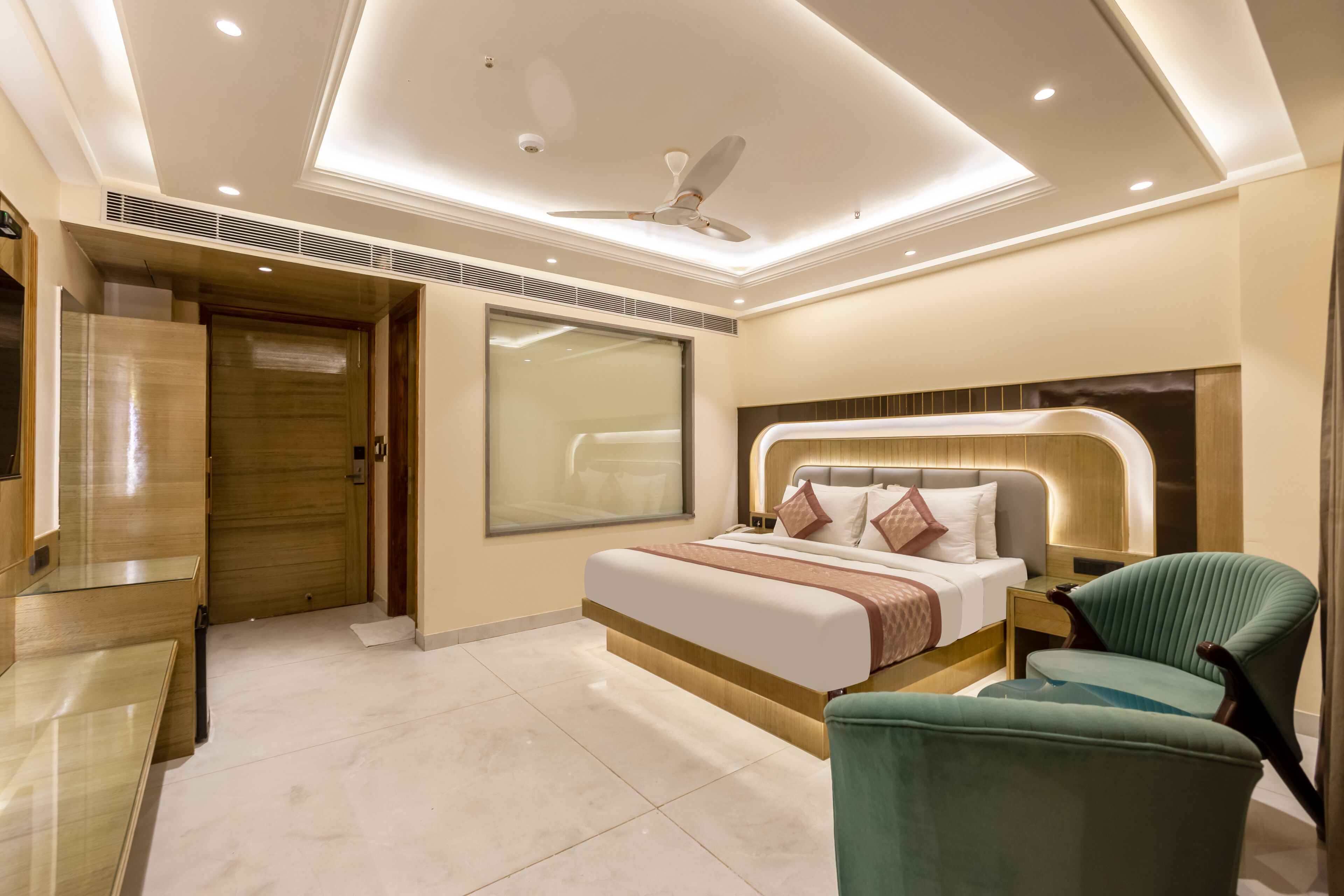A modern hotel room with a bed, a chair, a desk, and a ceiling fan.