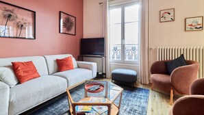 Un salon comprenant un canapé, un fauteuil, une table basse et des œuvres d’art accrochées aux murs.
