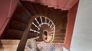 Un escalier en colimaçon en bois, avec un mur rouge et des carreaux de sol à motifs.