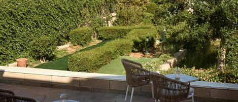 Un espace extérieur aménagé avec des chaises et une table en osier, offrant une vue sur un jardin bien entretenu et sur la mer.