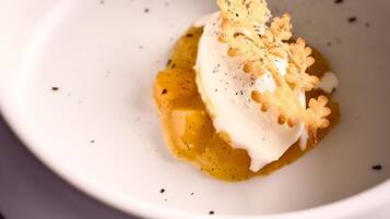 Un tazón blanco con un postre y cobertura cremosa, decorado con un adorno dorado.