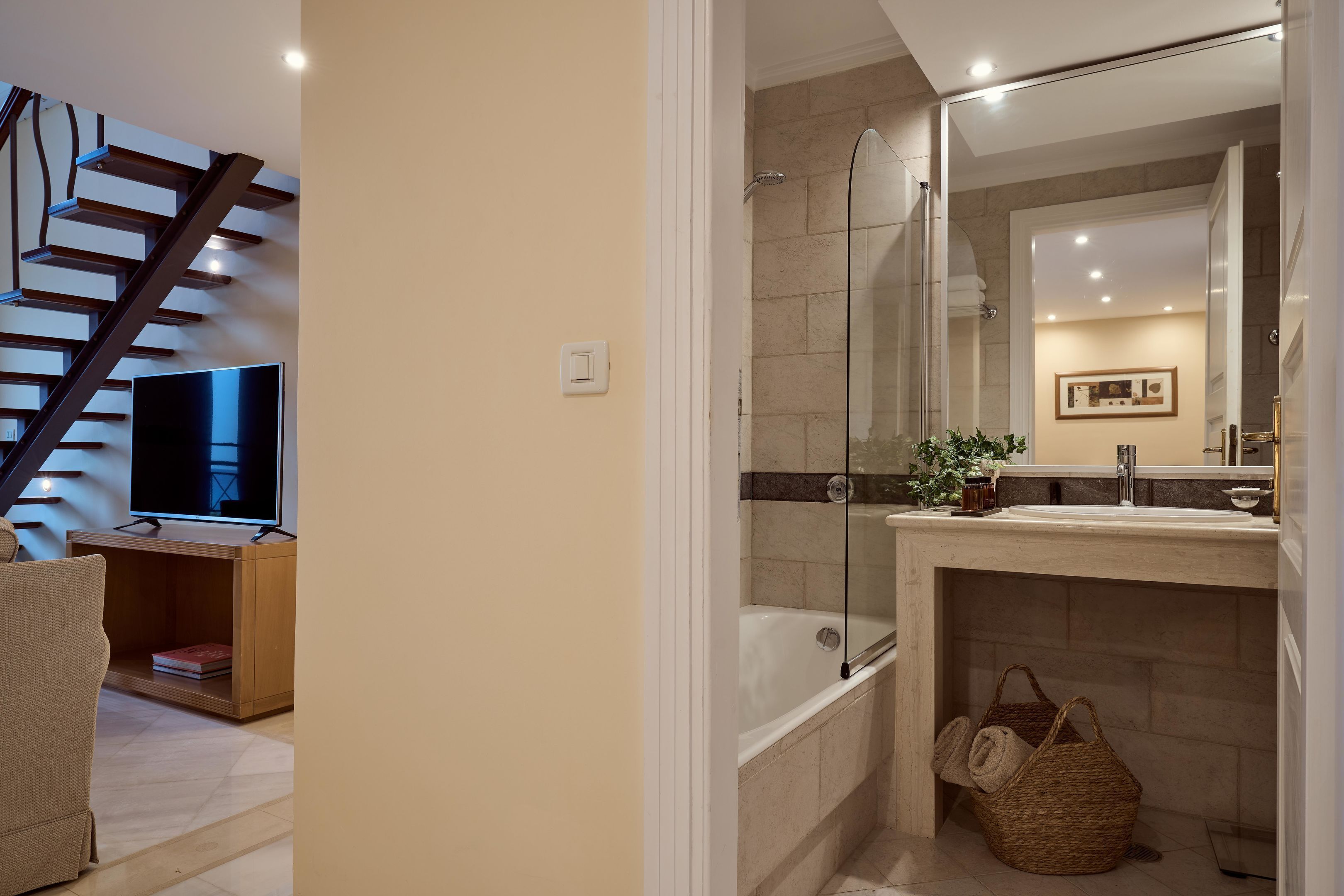 A modern bathroom with a glass-enclosed shower, a bathtub, and a vanity with a mirror.