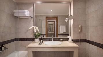 Un baño moderno con un espejo grande, un lavabo y una ducha.