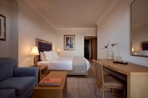Ein Hotelzimmer mit Bett, Schreibtisch, Stuhl, Sofa und Lampe.