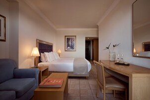 Una habitación de hotel con cama, escritorio, sillón, sofá y lámpara.