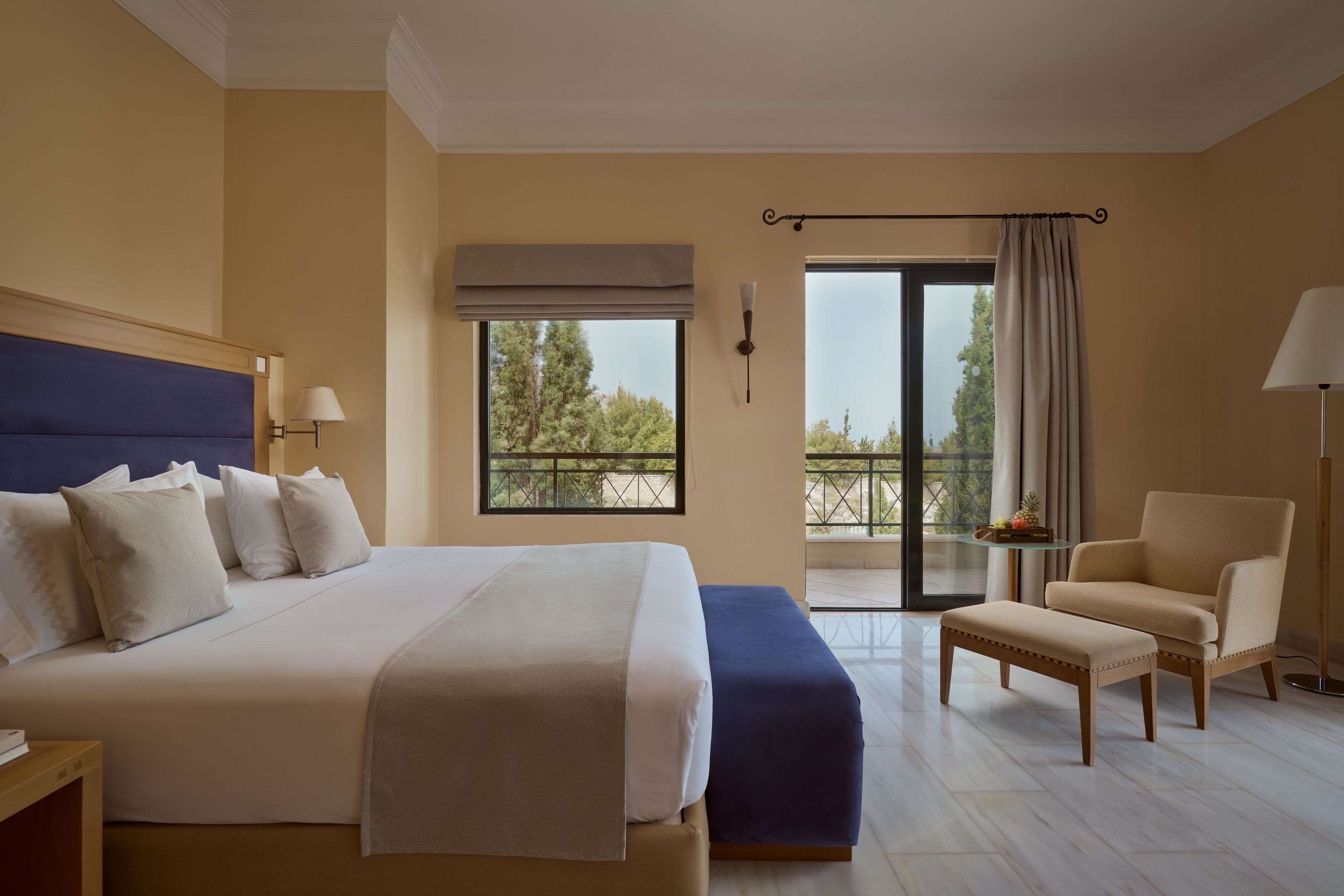 Una camera d'albergo con un letto grande, una sedia, un tavolino e un balcone con vista.