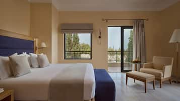 Una camera d'albergo con un letto grande, una sedia, un tavolino e un balcone con vista.