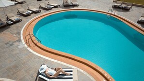 Una piscina con sillones de playa y tumbonas.