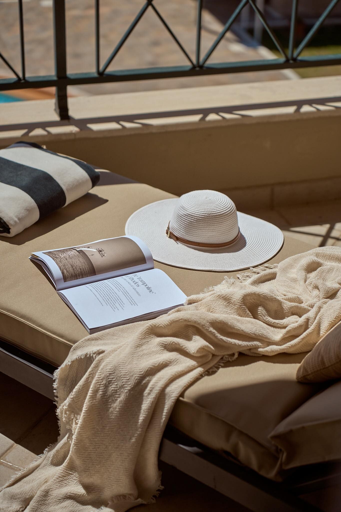 Una tumbona con un sombrero, un libro y una manta.