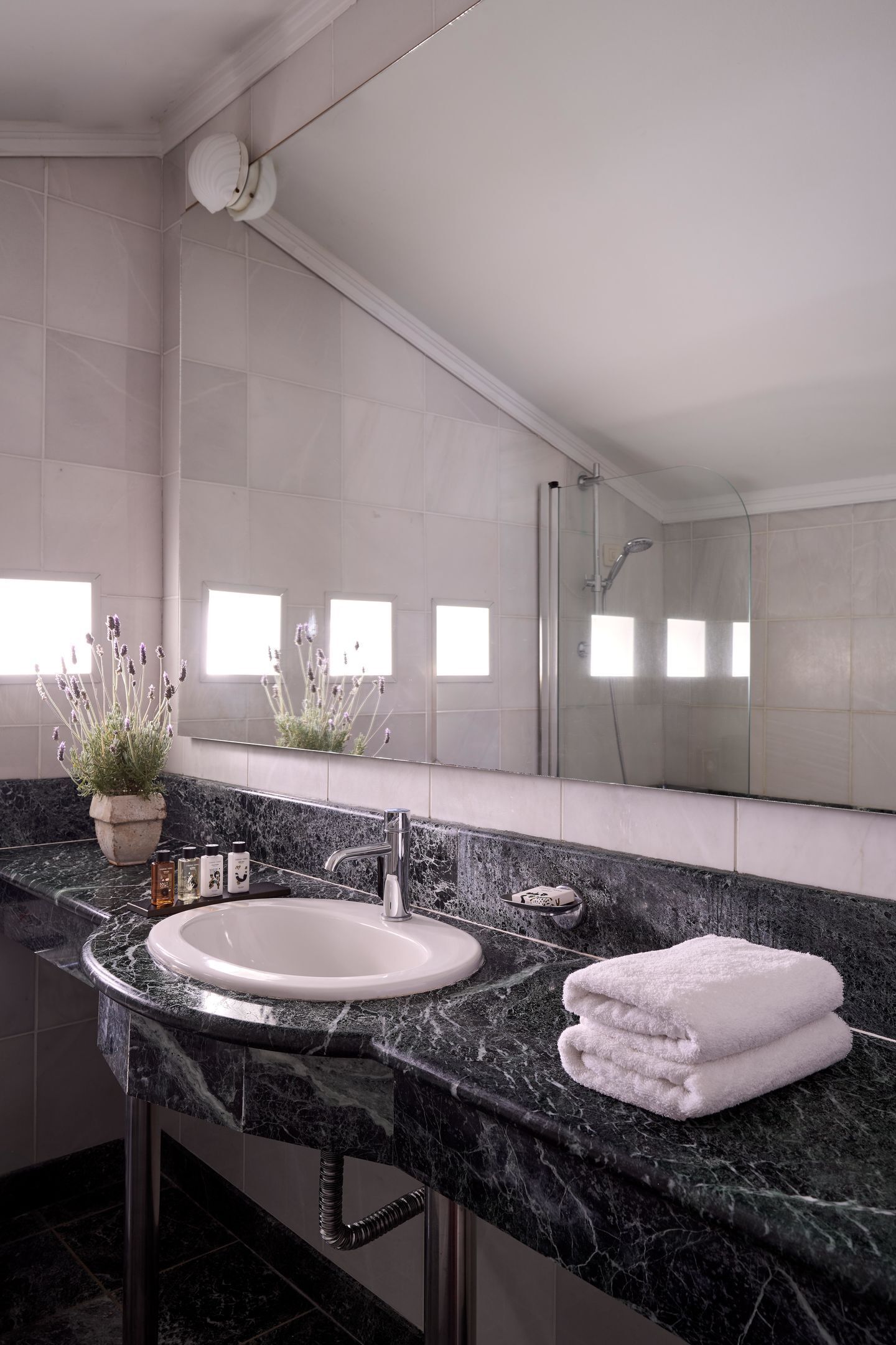 A modern bathroom with a marble sink, a large mirror, and a shower.