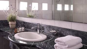 A modern bathroom with a marble sink, a large mirror, and a shower.