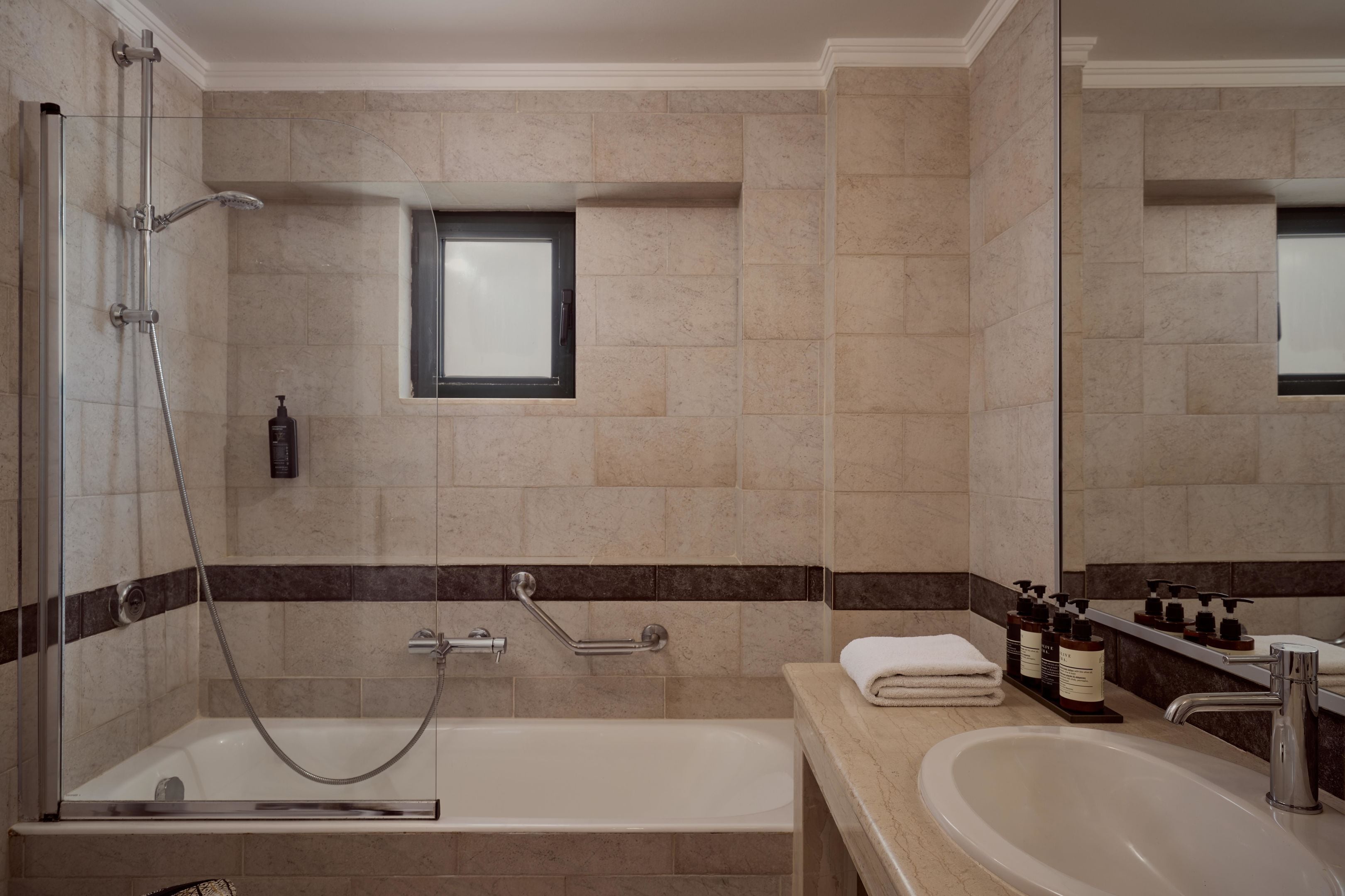 A modern bathroom with a glass-enclosed shower, a bathtub, a vanity with a sink, and a mirror.