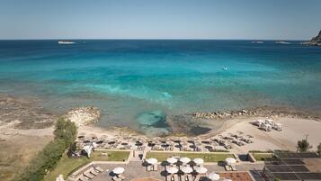 Un resort con piscina, tumbonas, sombrillas y vistas al mar.