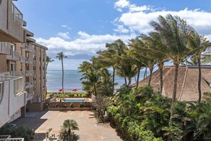 A hotel with a pool, palm trees, and a view of the ocean.