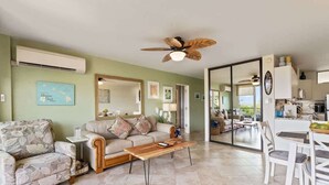 A living room with a sofa, coffee table, and dining area with chairs. - Partial oceanview 1 bedroom condo, AC, 6 mile sandy beach (Kihei)