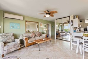 A living room with a sofa, coffee table, and dining area with chairs.