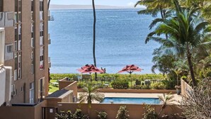 A hotel with a pool, palm trees, and a view of the ocean. - Partial oceanview 1 bedroom condo, AC, 6 mile sandy beach (Kihei)
