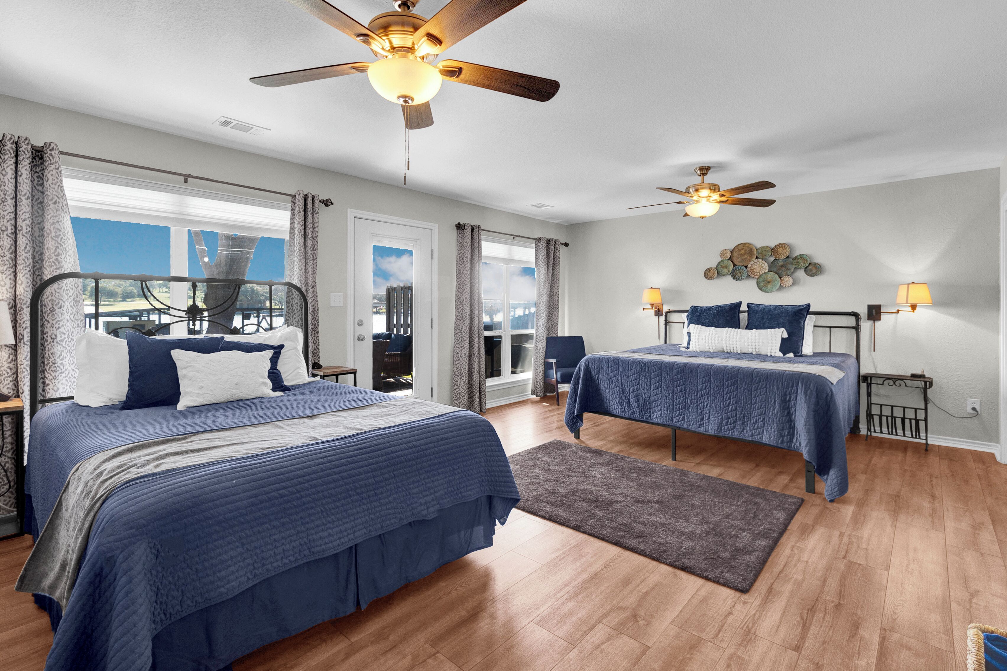 A bedroom with two beds, a ceiling fan, a view of the outdoors, and a rug.