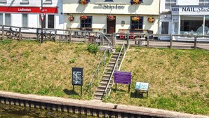 Un edificio con una insegna che recita 'The Ship Inn' e, adiacente, uno studio di bellezza 'Nails Nail Studio'.