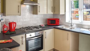 Cucina con piano cottura a gas, forno a microonde, forno e una finestra vista giardino.