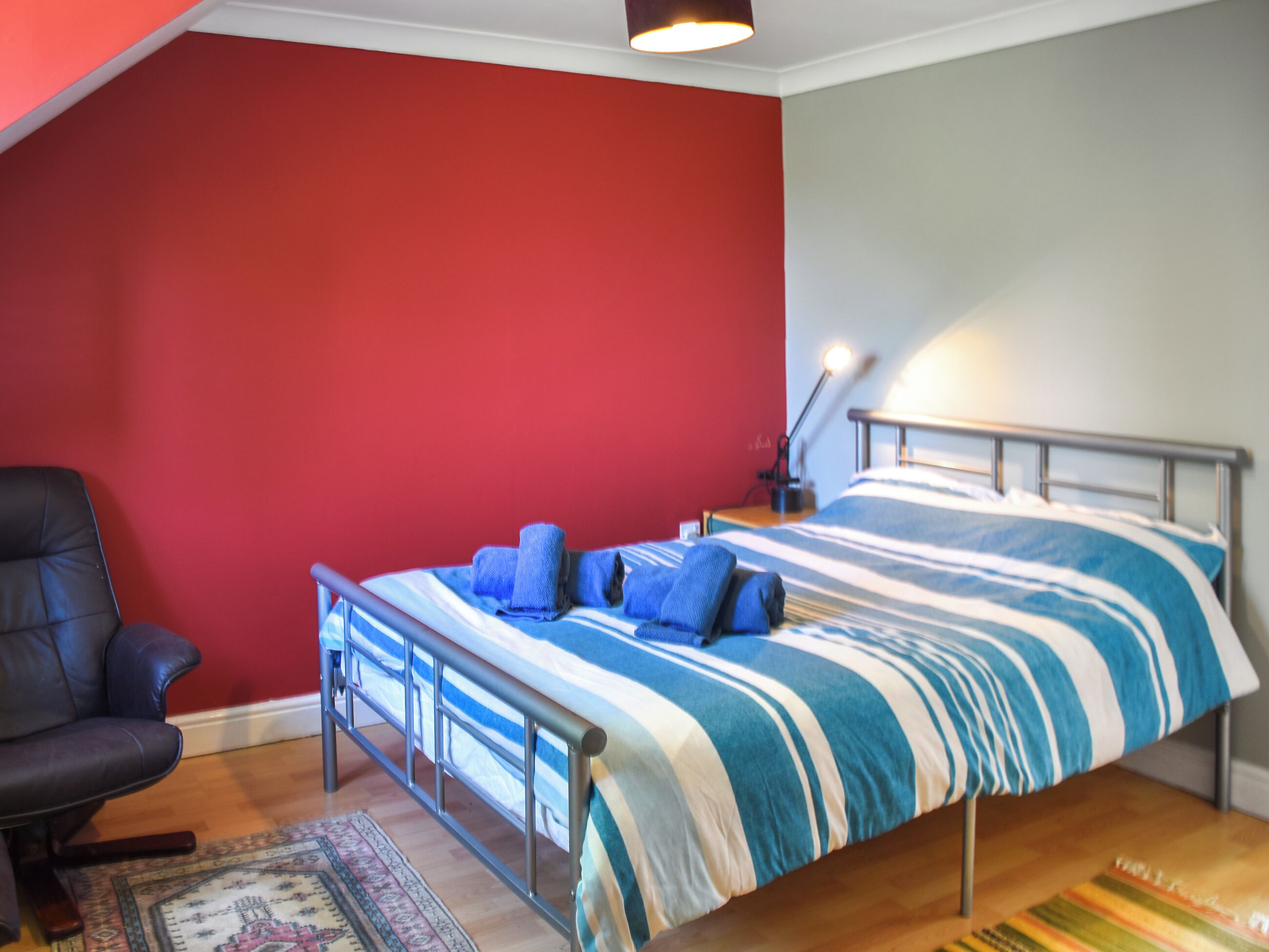 Une chambre à coucher avec un lit, une chaise et un bureau muni d’une lampe.