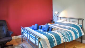 Une chambre à coucher avec un lit, une chaise et un bureau muni d’une lampe.