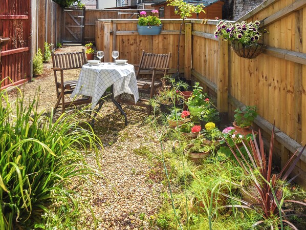 A wooden fence, a table with chairs, and various potted plants.