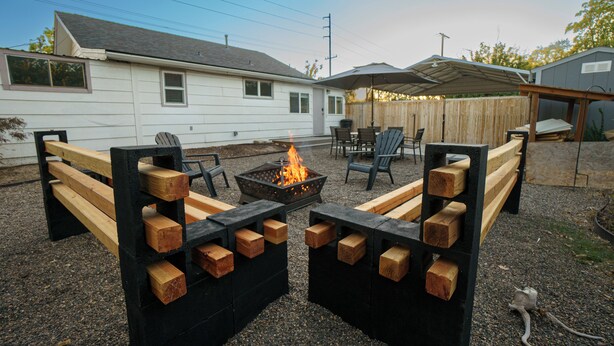 A backyard with a fire pit, wooden benches, and outdoor furniture.