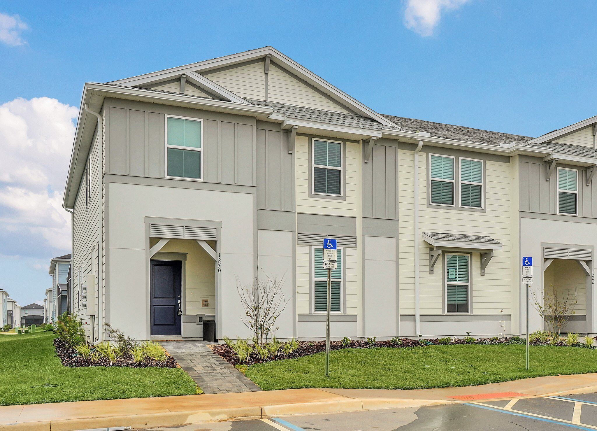 A two-story residential building with a front entrance, a small front yard, and a parking lot.
