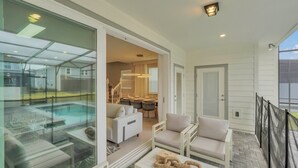 Ein Balkon mit Glasveranda, ein Pool, eine Essecke mit Tisch und Stühlen sowie eine Sitzecke mit Sofa und Sesseln.