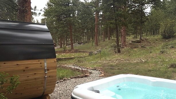 Un jacuzzi rodeado por un área boscosa, con una estructura de madera cerca.
