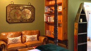 Una habitación acogedora con un sofá de cuero, una amplia estantería y un adorno de pared decorativo.